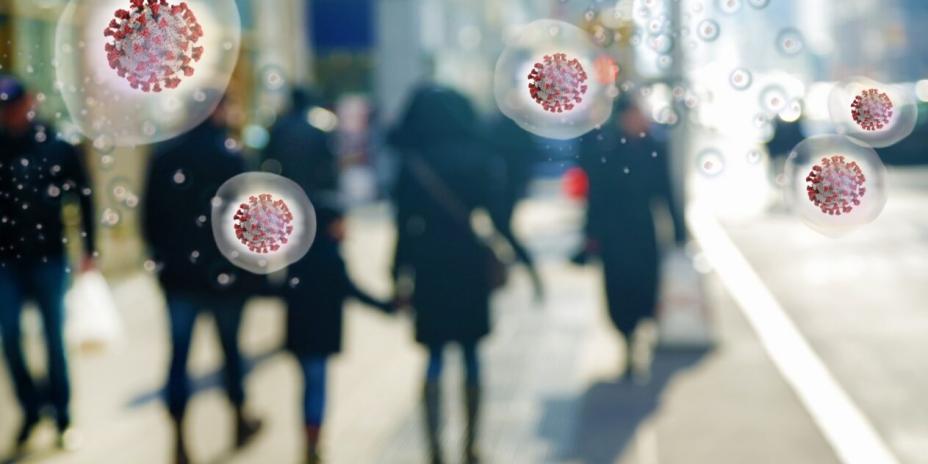 silhouetted people walking on a city street with five red circular virus particles representing COVID on top of them